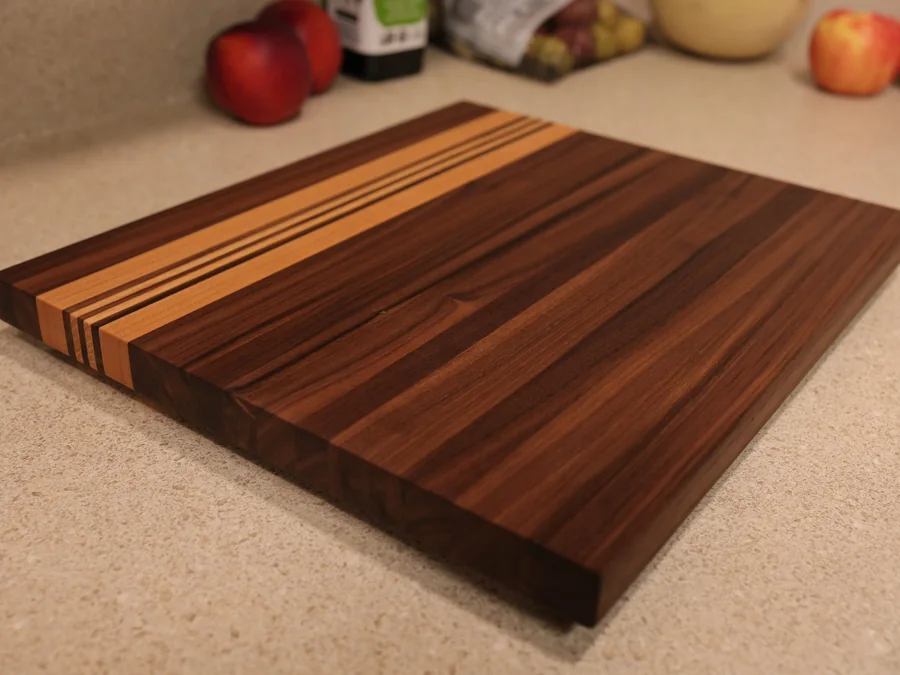Dark hardwood cutting board with contrasting maple stripes